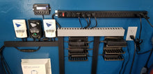 Load image into Gallery viewer, An organized outlet wall, featuring a long outlet strip, cords with excess zip tied, and six Power Brick Stackable Mounts. Each one is holding a power brick.