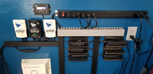 Load image into Gallery viewer, An organized outlet wall, featuring a long outlet strip, cords with excess zip tied, and six Power Brick Stackable Mounts. Each one is holding a power brick.  
